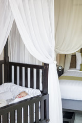 Adorable blonde baby sleeping in a crib, view from above