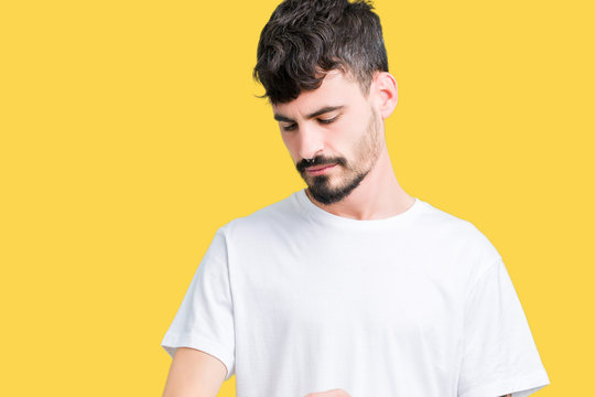 Young handsome man wearing white t-shirt over isolated background Checking the time on wrist watch, relaxed and confident