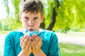 teen boy holding piggy Bank on nature background