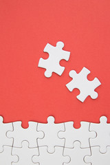 White jigsaw puzzle pieces on red background with negative space