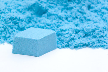 Closeup og blue kinetic sand on the white background. Kids development concept.