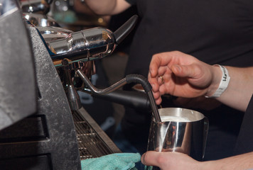 Close-up of hands of barista heating milk in a coffee machine for a client. Man makes coffee in the coffee machine.