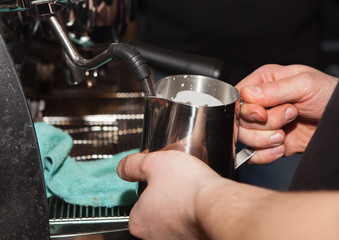 Close-up of a barista eating milk in coffee. Barista makes coffee for customers.