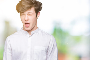 Young handsome business man over isolated background winking looking at the camera with sexy...