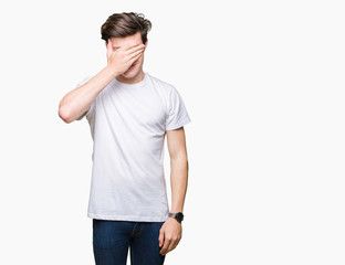 Fototapeta premium Young handsome man wearing casual white t-shirt over isolated background smiling and laughing with hand on face covering eyes for surprise. Blind concept.