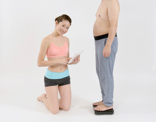 太った男性の体重を量る女性