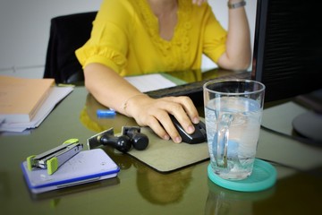 The young woman is working with a computer sitting in a low light