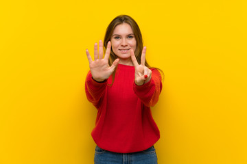 Young woman over yellow wall counting seven with fingers