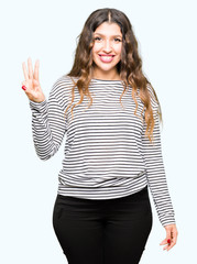 Young beautiful woman wearing stripes sweater showing and pointing up with fingers number three while smiling confident and happy.