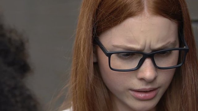 Female student saying hurtful offensive comments to girl, bullying closeup