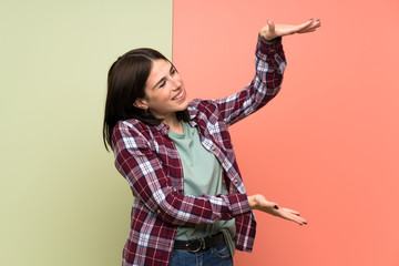 Young woman over isolated colorful wall holding copyspace to insert an ad