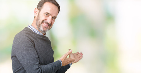 Naklejka na ściany i meble Handsome middle age senior man wearing a sweater over isolated background Inviting to enter smiling natural with open hand
