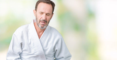 Handsome middle age senior man wearing kimono uniform over isolated background with hand on stomach because indigestion, painful illness feeling unwell. Ache concept.