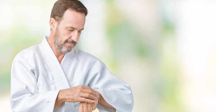 Handsome middle age senior man wearing kimono uniform over isolated background Checking the time on wrist watch, relaxed and confident