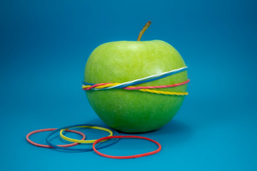 Green apple tied in colorful rubber bands