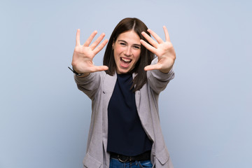 Young woman over isolated blue wall counting ten with fingers