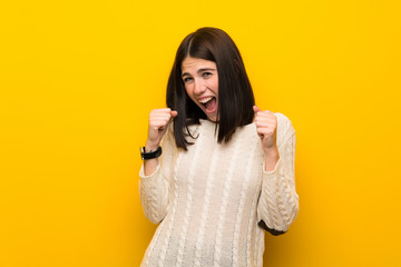 Young woman over isolated yellow wall celebrating a victory in winner position