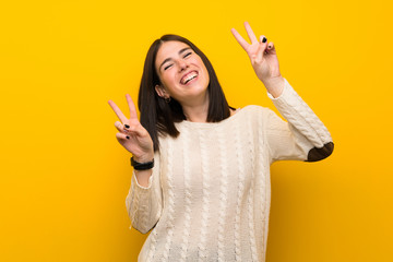 Young woman over isolated yellow wall showing victory sign with both hands