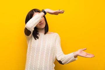 Young woman over isolated yellow wall holding copyspace to insert an ad