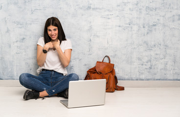 Student woman sitting on the floor with surprise facial expression
