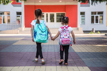 Back to school education concept with girl kids, elementary students, carrying backpacks going to class