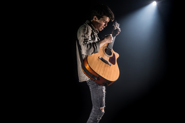 Guitarist, music. A young man plays an acoustic guitar on a black isolated background