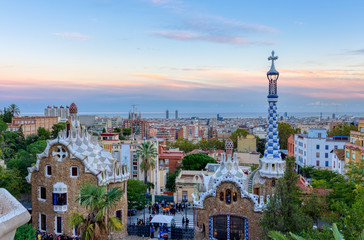 View of Barcelona from Park Guell at the sunset. In the foreground the colourful buildings of the main entrance. Barcelona.