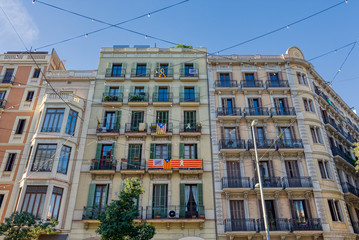 Facades of buildings around Barcelona with some flags of Catalonia hanging on the balconies