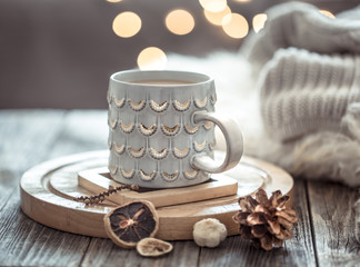 Coffee cup over Christmas lights bokeh in home on wooden table with sweater on a background and decorations. Holiday decoration, magic Christmas