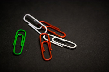 A set of multi-colored office paper clips of plastic are scattered on black monophonic background. 