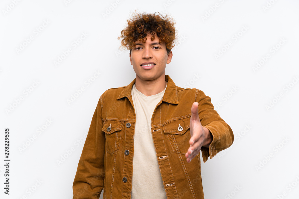 Wall mural young african american man over isolated white wall handshaking after good deal