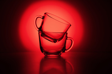 Two transparent cups stand on a table against a red background.