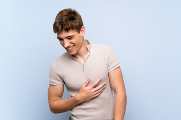 Handsome young man over isolated blue wall smiling a lot