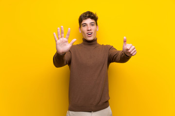 Handsome young man over isolated yellow background counting six with fingers