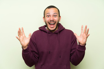 Fototapeta premium Colombian man with sweatshirt over green wall with surprise facial expression