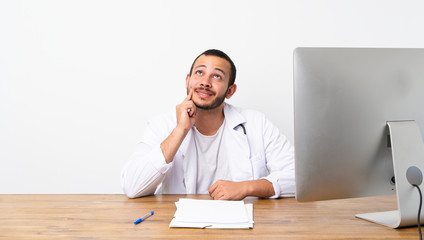 Doctor Colombian man thinking an idea while looking up