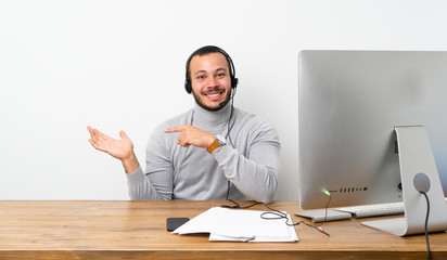 Telemarketer Colombian man holding copyspace imaginary on the palm to insert an ad