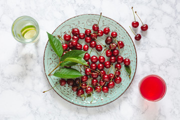 Fresh cherries with leaves on a plate