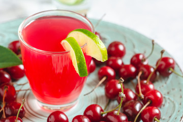 Glass with cherry compote, fresh cherries on a plate.