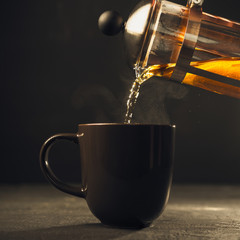The process of pouring black tea into a Cup,dark background,