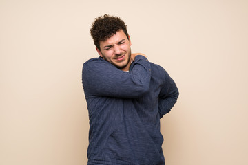 Man with curly hair over isolated wall suffering from pain in shoulder for having made an effort