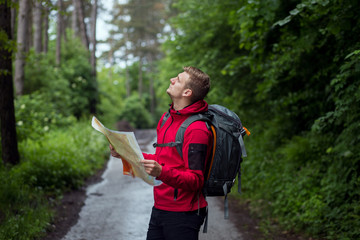 Male hiker with backpack using map to navigate in nature