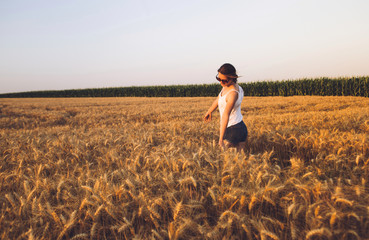 Naklejka na ściany i meble Young Woman running through Wheat Field in summer