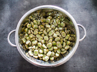 Broad beans in strainer on stone table