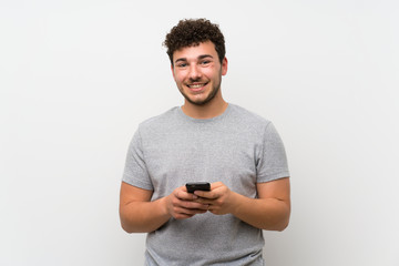 Man with curly hair over isolated wall using mobile phone