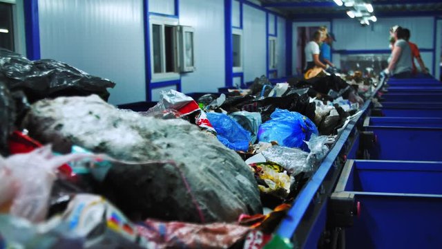 Workers at conveyor sorting garbage at a recycling plant. 4K (UHD)