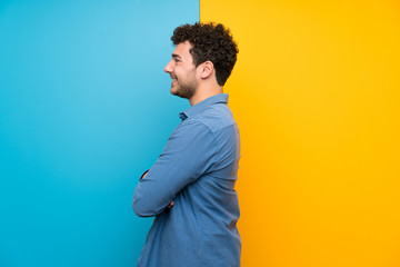 Man with curly hair over colorful wall in lateral position