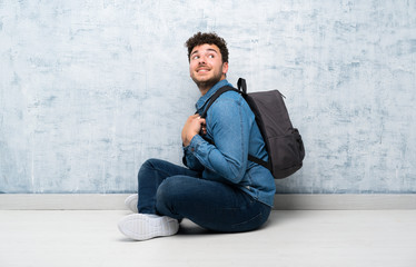 Young man sitting on the floor with backpack