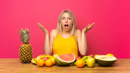 Obraz premium Young blonde woman with lots of fruits with surprise facial expression