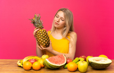 Obraz premium Young woman with lots of fruits holding a pineapple